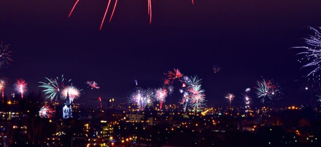 Vibrant fireworks light up the night sky over a city. Perfect for celebrations or festive events.